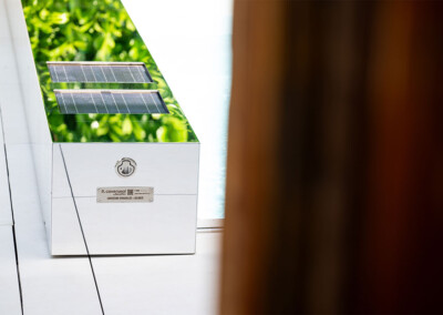 Habillage effet miroir de la Coverseal avec finition inox polie reflétant la végétation, équipé de panneaux solaires intégrés pour l’alimentation.