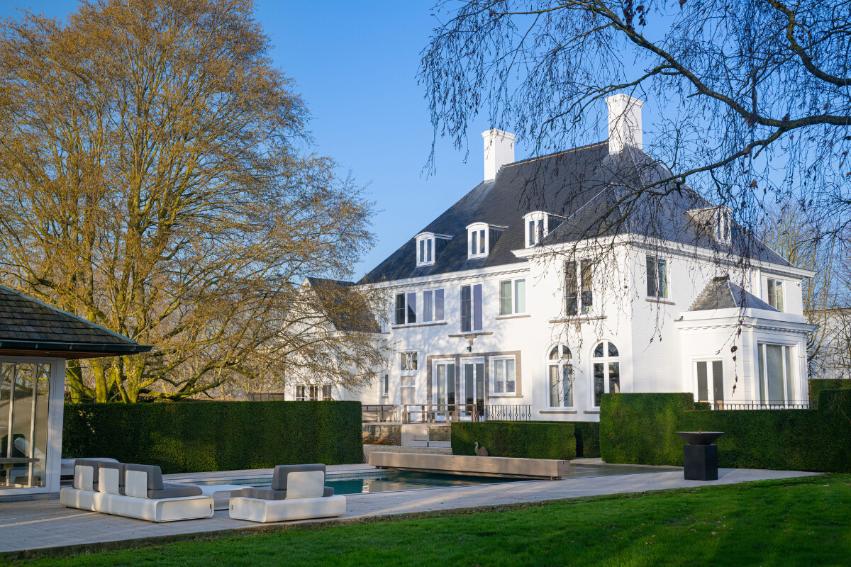 Gros plan sur l'habillage de la Coverseal grise au bord de la piscine, avec en arrière-plan les transats et la maison en pierre.